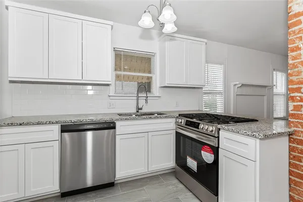 a kitchen with cabinets appliances a sink and a window