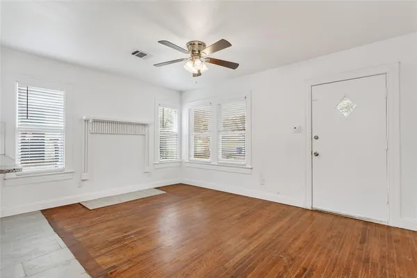 an empty room with wooden floor fan and windows