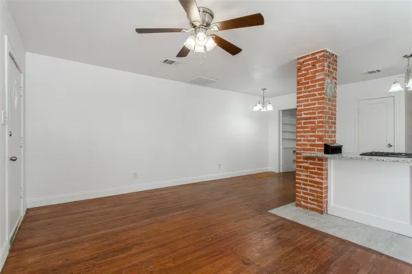 wooden floor in an empty room with a chandelier fan