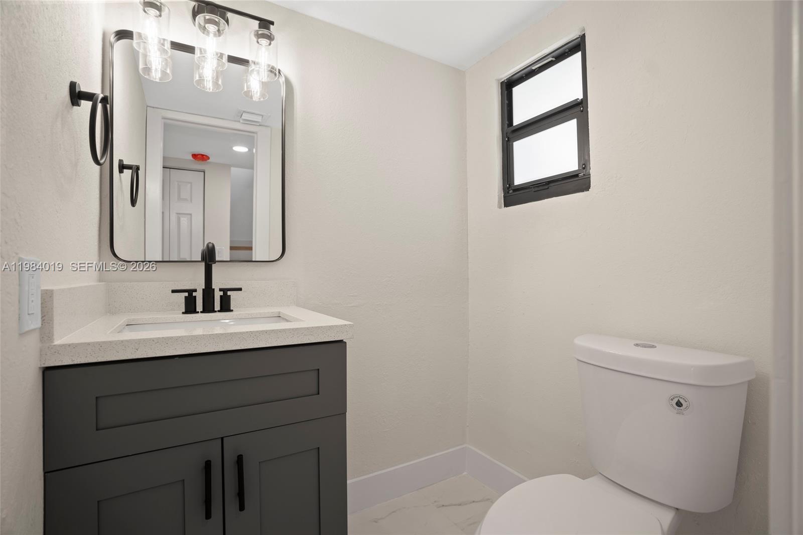 28015 Southwest 143rd Court Homestead, FL 33033 - Photo 12 of 29 a bathroom with a toilet a sink and mirror