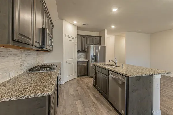 a kitchen with stainless steel appliances granite countertop a stove a sink and a refrigerator