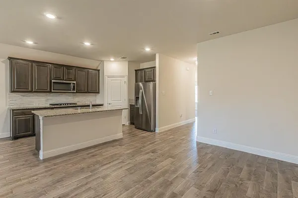 a large kitchen with stainless steel appliances granite countertop a stove a sink dishwasher and a oven with wooden floors