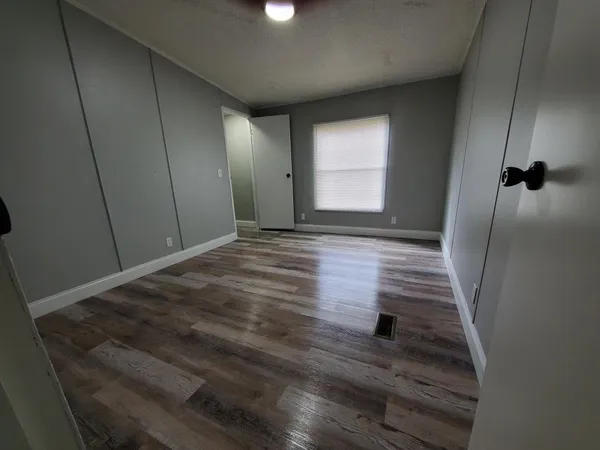 a view of an empty room with wooden floor and a window