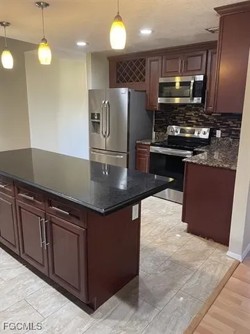 a kitchen with stainless steel appliances granite countertop a sink wooden cabinets and a stove