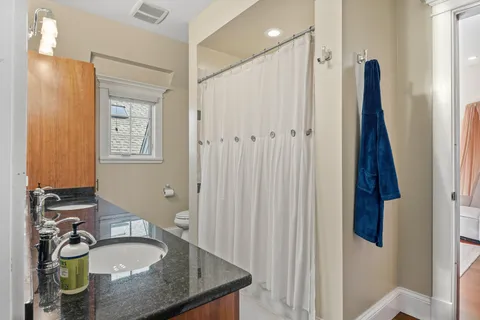 a bathroom with a granite countertop sink toilet and shower