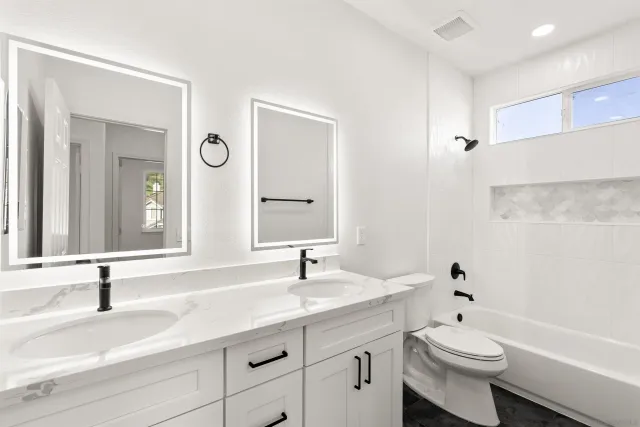 a bathroom with a double vanity sink toilet and a mirror