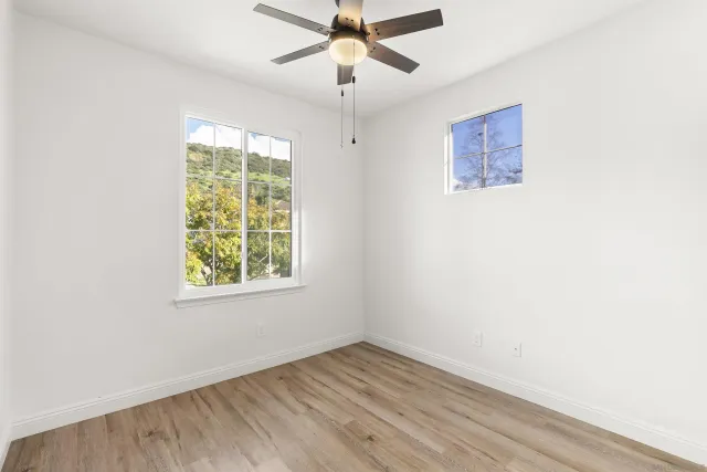 an empty room with a window and a fan