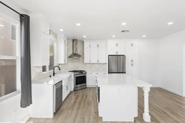 a large kitchen with stainless steel appliances granite countertop a large stove a sink dishwasher and a refrigerator with wooden floor