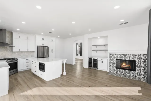 a living room with stainless steel appliances furniture a fireplace a flat screen tv and view kitchen