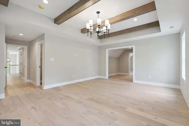 a view of an empty room with chandelier and wooden floor