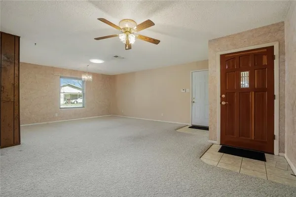 an empty room with windows and chandelier fan