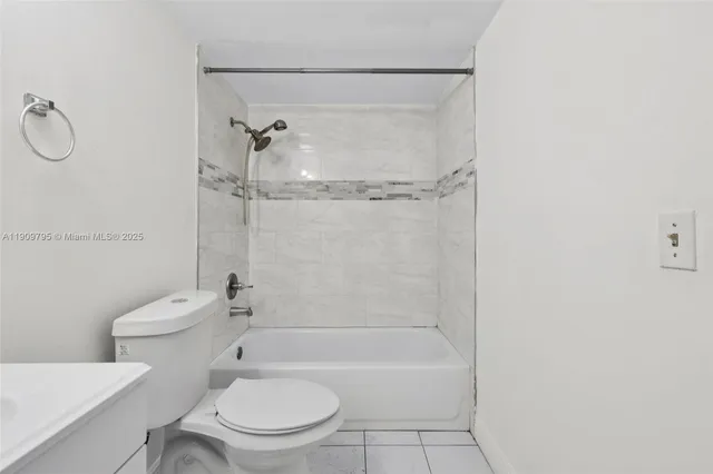 a bathroom with a granite countertop bathtub shower sink vanity and toilet