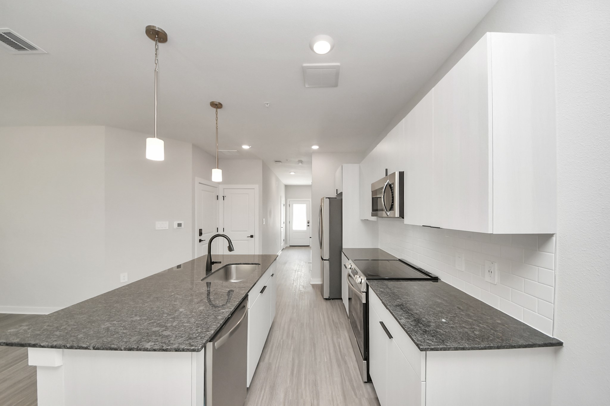 7711 Longmire Road, Unit 102 Conroe, TX 77304 - Photo 44 of 48 Boasting luxury finishes-stylish Island kitchen,granite counters,subway tile backsplash,ample custom cabinet space,stainless appliances,refrigerator,full size washer&dryer included,wood-like floors throughout,open concept floor plan.