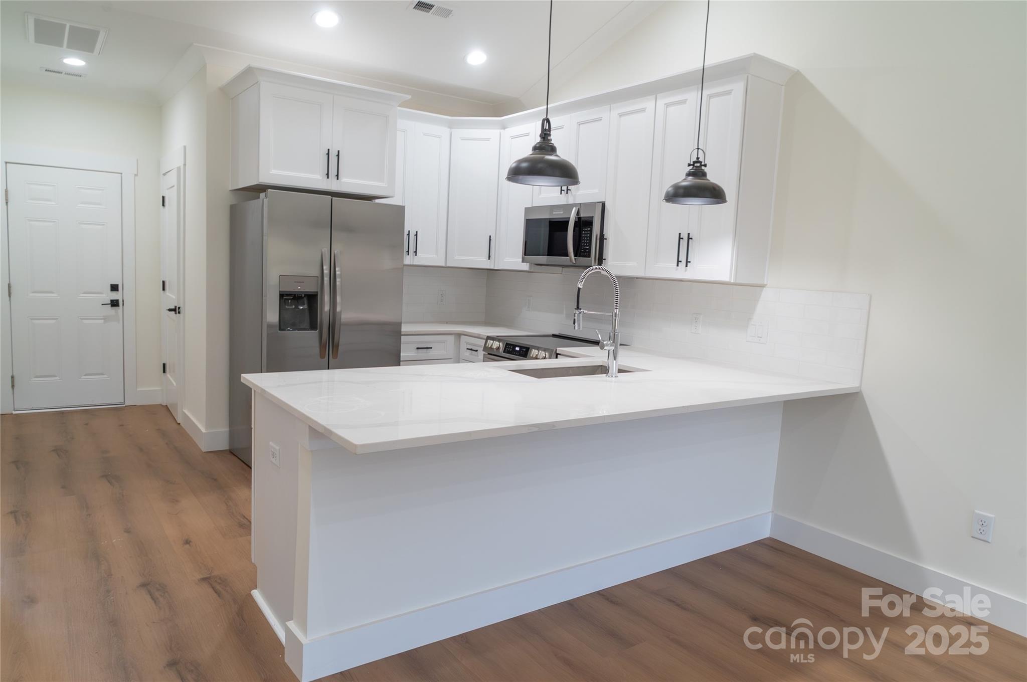 102 Ivy Court Morganton, NC 28655 - Photo 2 of 11 a kitchen with stainless steel appliances a refrigerator a sink dishwasher a stove and white cabinets with wooden floor