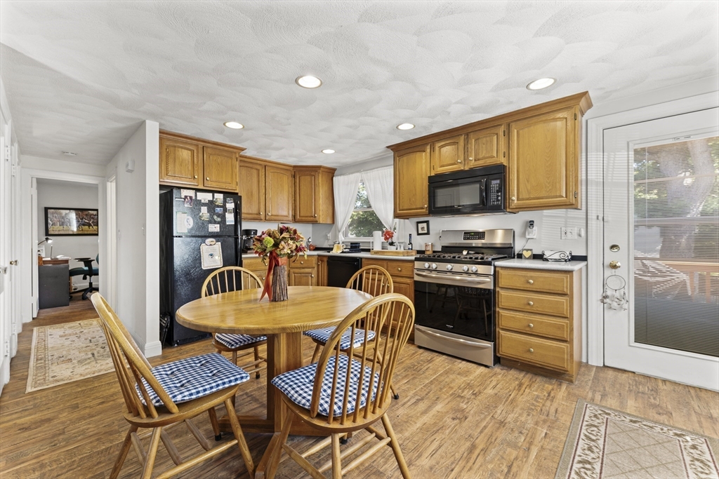 85 Oak Street Stoneham, MA 02180 - Photo 10 of 35 a kitchen with a refrigerator a stove top oven a sink dishwasher and a dining table with wooden floor