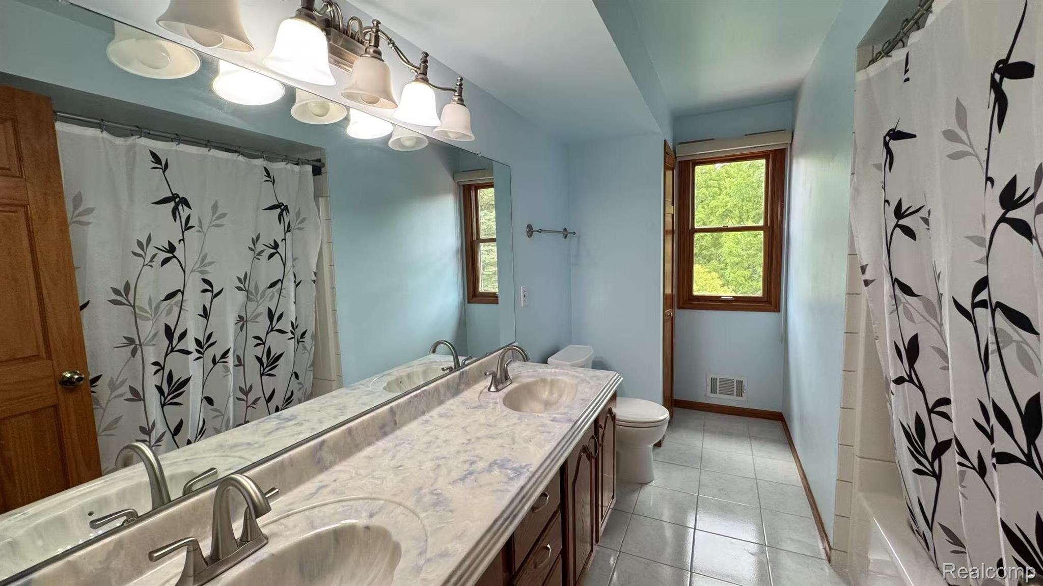 3440 Salem Drive Rochester, MI 48306 - Photo 25 of 33 Dual vanity with integrated sinks, a substantial wall-mounted mirror, and a multi-bulb light fixture