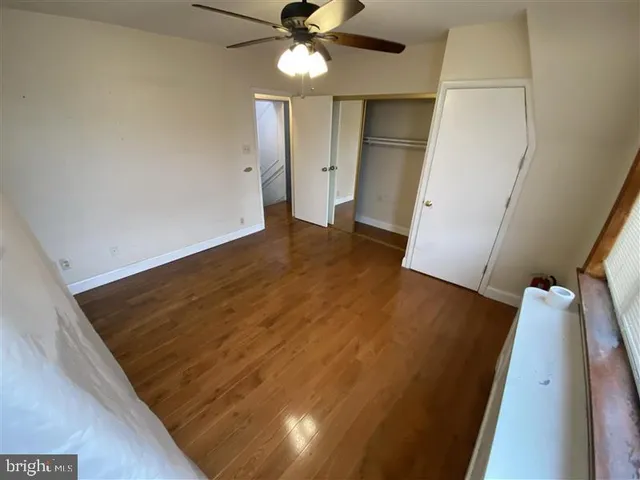 an empty room with wooden floor fan and window