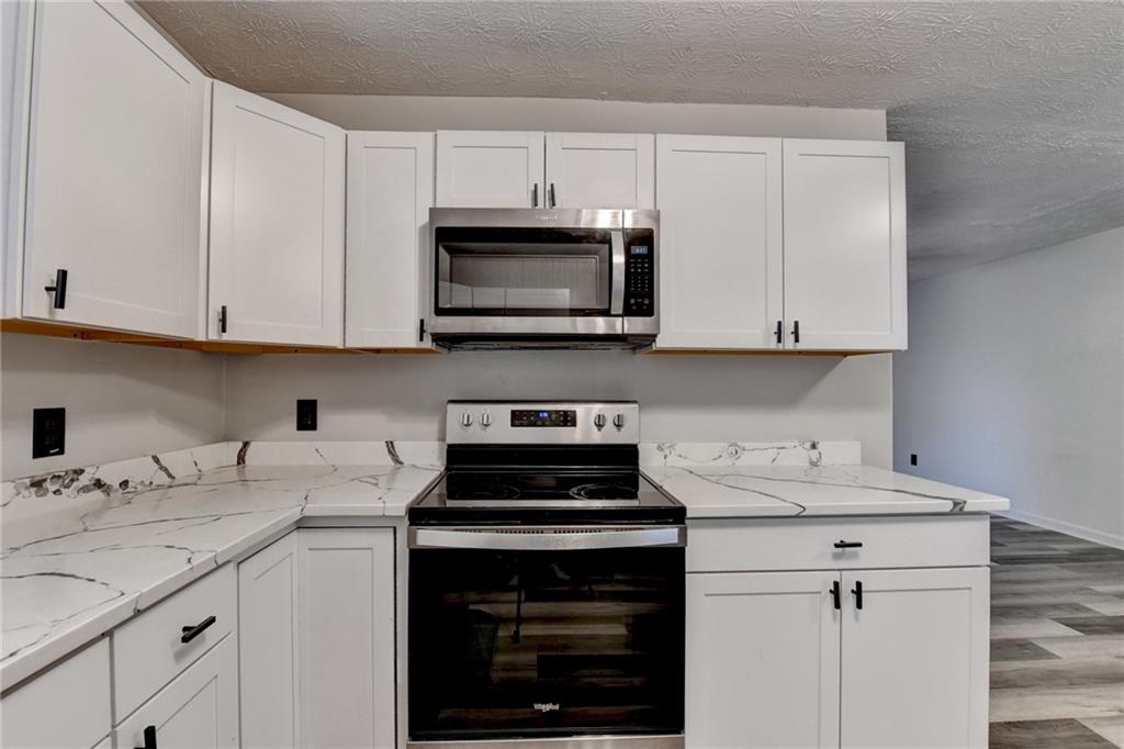 801 Davis Street Monroe, GA 30655 - Photo 13 of 33 a kitchen with granite countertop a stove sink and cabinets
