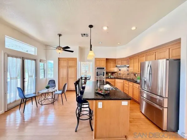 a kitchen with stainless steel appliances granite countertop a refrigerator a oven a stove and a dining table with wooden floor