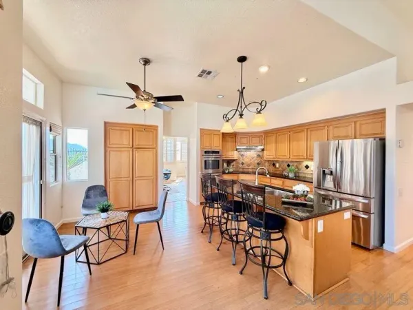 a kitchen with stainless steel appliances kitchen island granite countertop a table chairs and a refrigerator