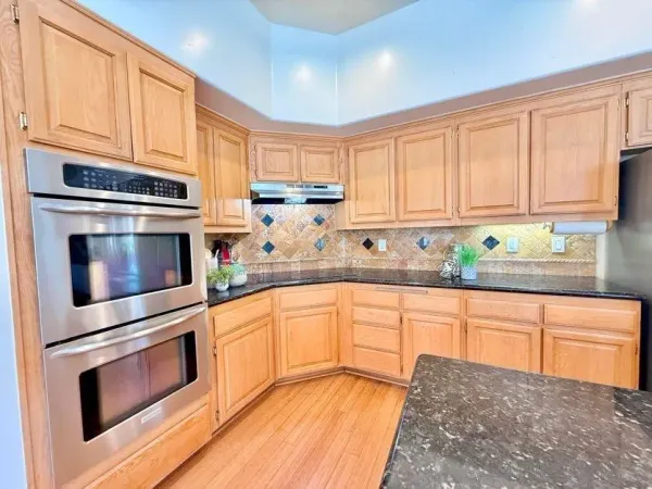 a kitchen with granite countertop white cabinets stainless steel appliances and a window