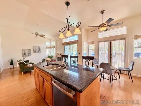 a kitchen with granite countertop a table chairs stove and flat screen tv
