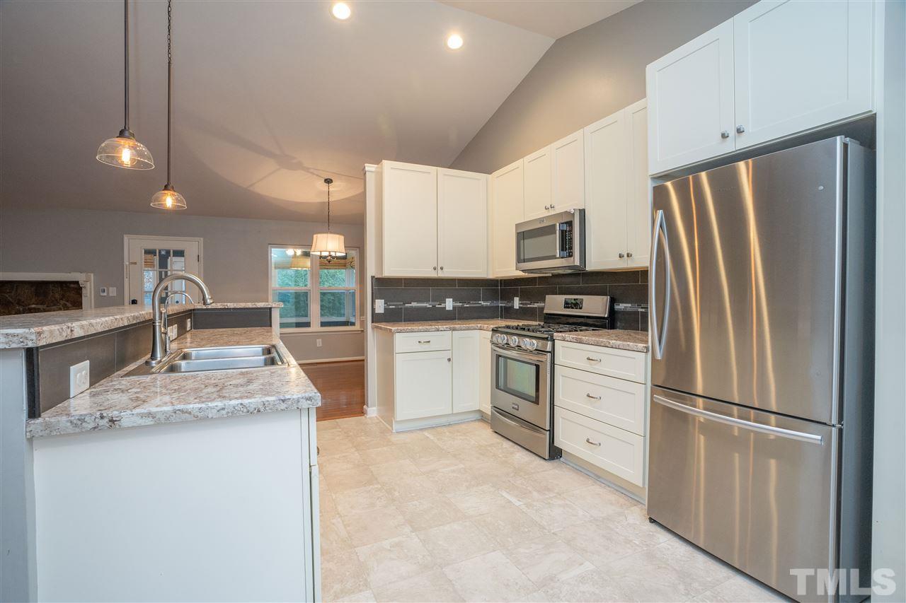 5400 Chilham Place Raleigh, NC 27612 - Photo 5 of 25 a kitchen with white cabinets and stainless steel appliances