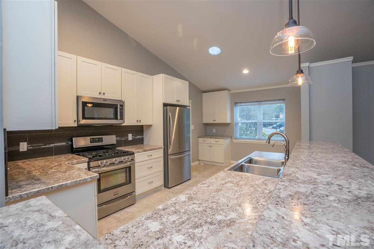 5400 Chilham Place Raleigh, NC 27612 - Photo 6 of 25 a kitchen with granite countertop a refrigerator and a stove top oven