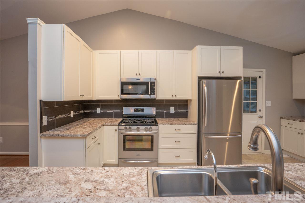 5400 Chilham Place Raleigh, NC 27612 - Photo 7 of 25 a kitchen with stainless steel appliances granite countertop a refrigerator sink and stove