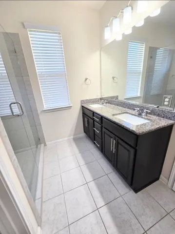 a spacious bathroom with a granite countertop sink a mirror and a bathtub