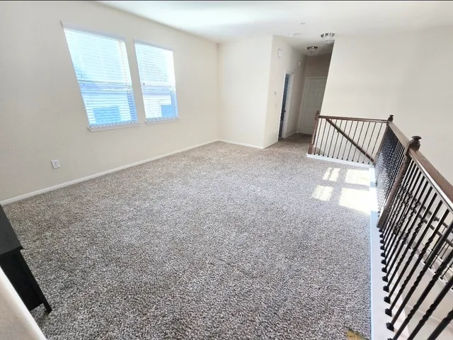 an empty room with a chandelier fan and windows
