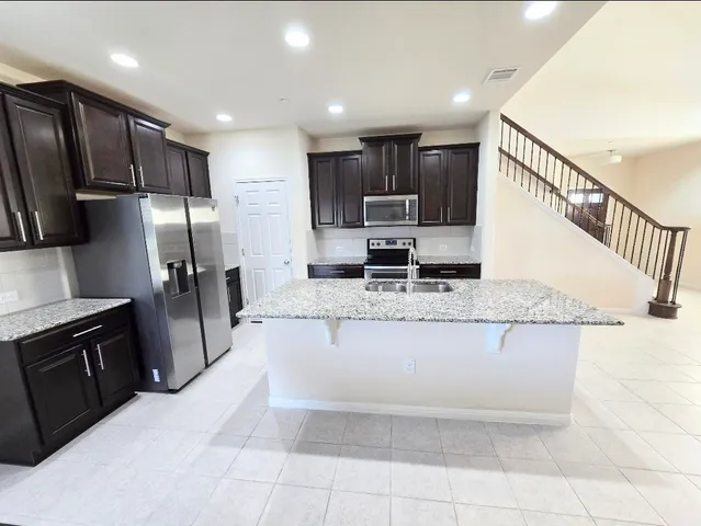 a kitchen with stainless steel appliances granite countertop a refrigerator a sink a stove a microwave and island