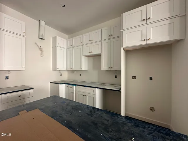 a kitchen with stainless steel appliances granite countertop a refrigerator a sink and white cabinets