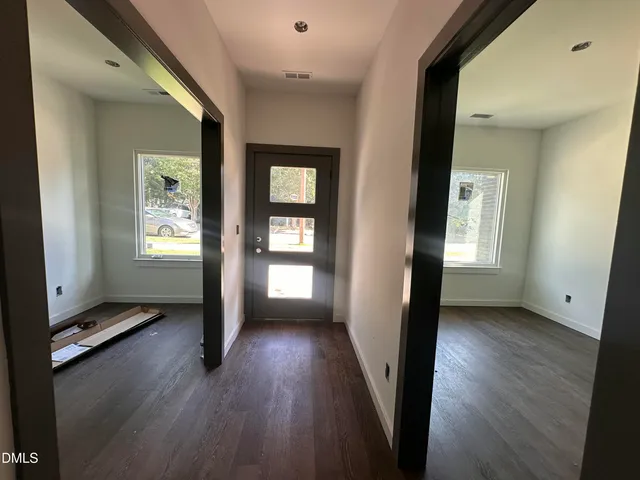 a view of a hallway with wooden floor and a living room