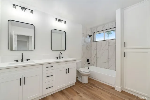 a bathroom with a double vanity sink a toilet and a bathtub