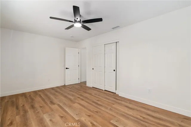 a view of a room with wooden floor and a ceiling fan