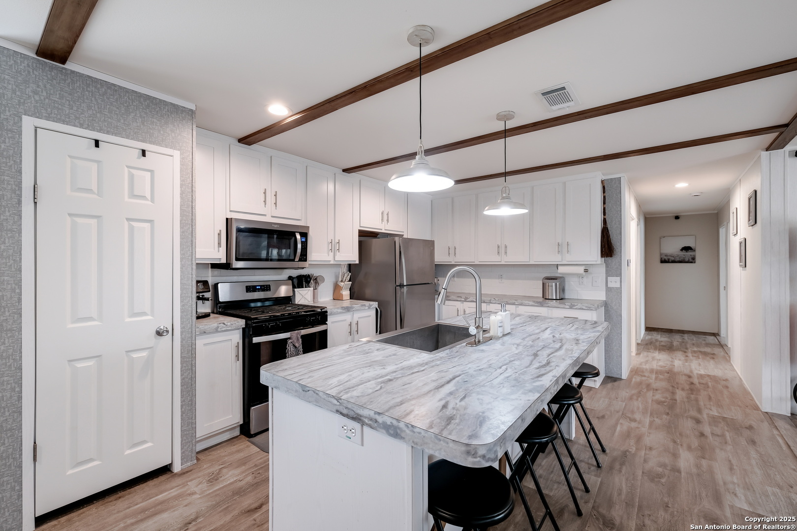 753 Pr Riley Lane Charlotte, TX 78011 - Photo 7 of 22 a kitchen with stainless steel appliances kitchen island granite countertop a table chairs refrigerator and microwave