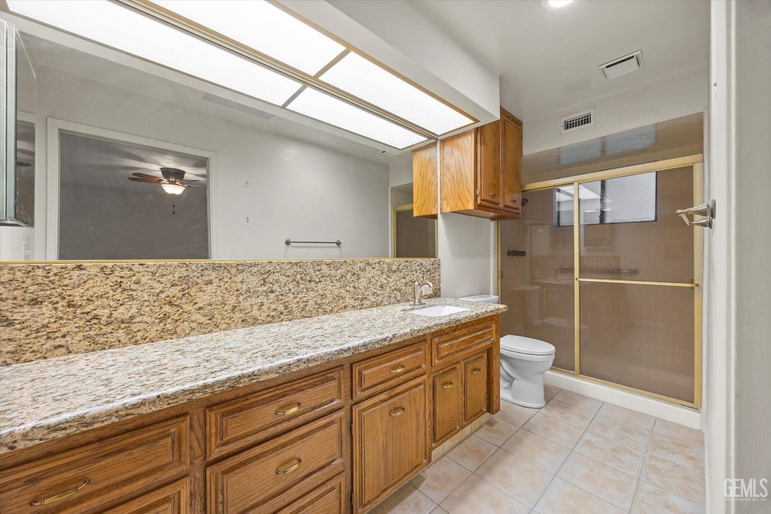 Undisclosed Address Bakersfield, CA 93309 - Photo 24 of 36 a bathroom with a granite countertop sink a toilet and shower