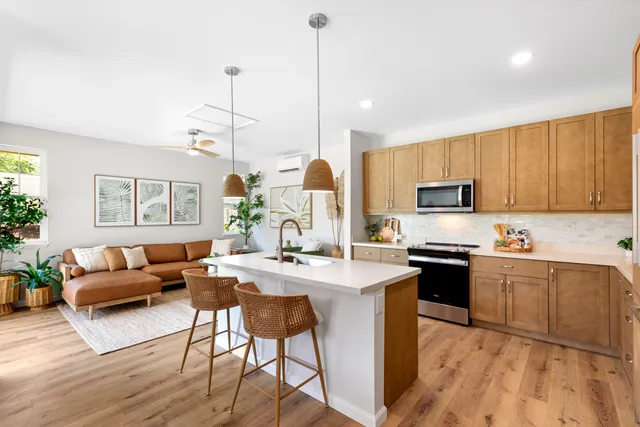 a kitchen with stainless steel appliances granite countertop a stove top oven a sink dishwasher a dining table and chairs with wooden floor