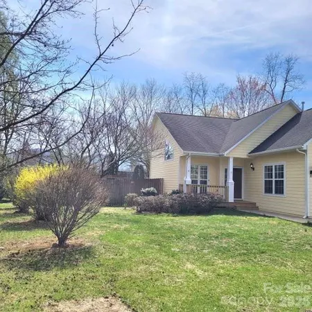 a view of a house with a big yard plants and large tree