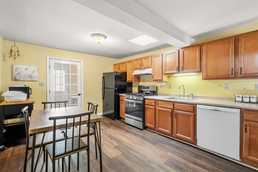 90 Loring Avenue Whitman, MA 02382 - Photo 7 of 22 a kitchen with granite countertop a stove top oven a sink dishwasher a dining table and chairs with wooden floor