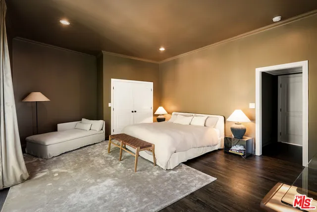 a bedroom with a bed wooden floor and couch