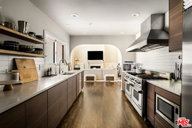 a kitchen with stainless steel appliances a stove top oven a sink dishwasher and a microwave with wooden floor