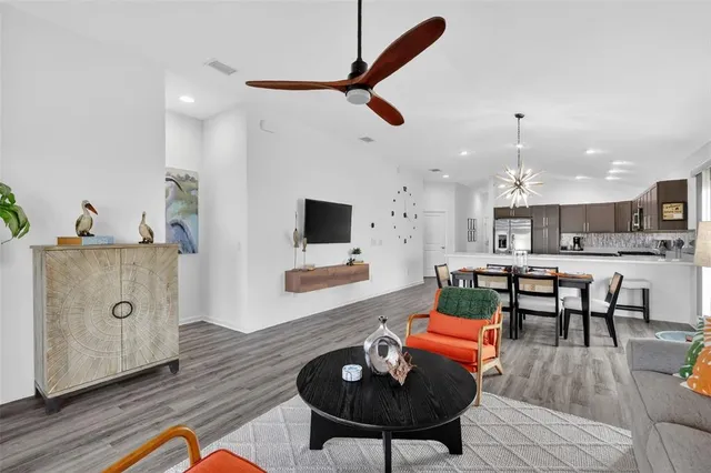 a living room with furniture kitchen view and a wooden floor