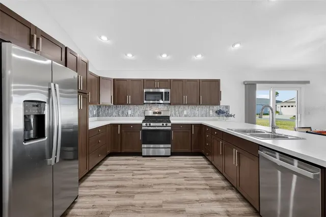 a large kitchen with stainless steel appliances granite countertop a refrigerator a sink dishwasher a oven with wooden cabinets and a granite countertops