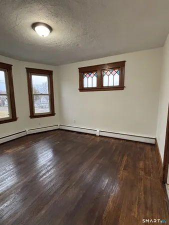 a view of an empty room with wooden floor and a window