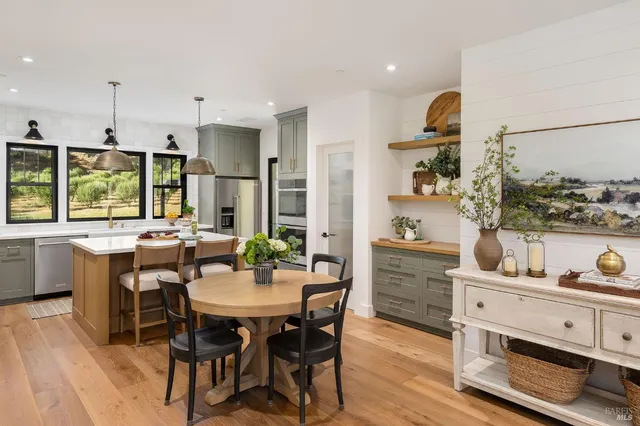 a kitchen with stainless steel appliances kitchen island granite countertop a stove a sink a dining table and chairs