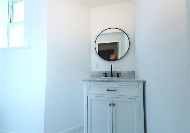 a bathroom with a granite countertop sink and a mirror