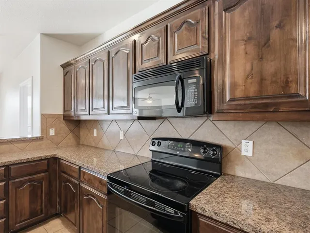 a kitchen with granite countertop cabinets stove top oven and microwave
