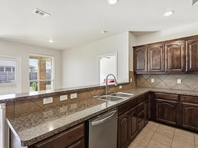 a kitchen with granite countertop stainless steel appliances a sink window and cabinets